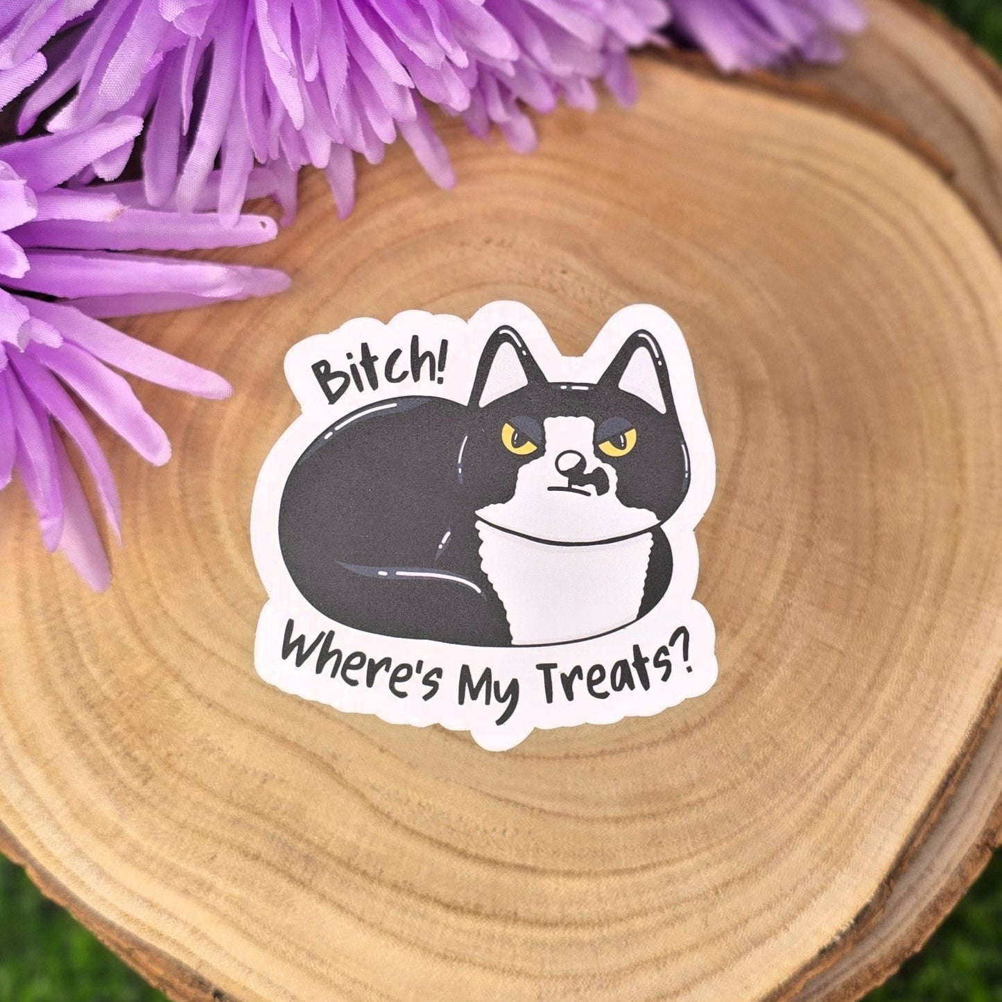 Sticker of a cat with text on a wooden surface with purple flowers