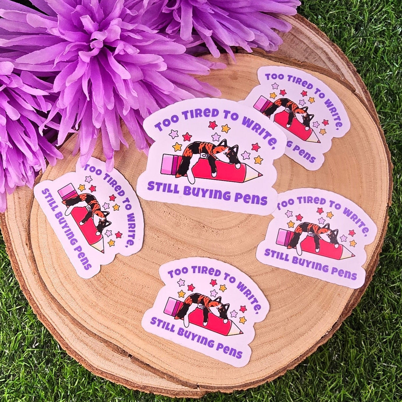 Stickers with a cat design on a wooden surface with purple flowers.