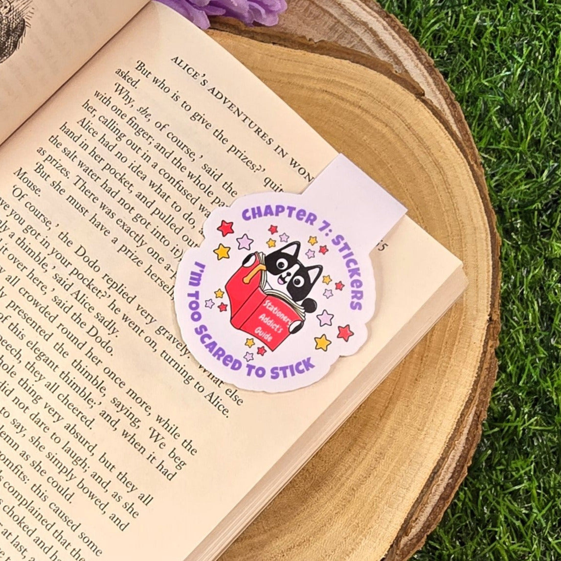 Open book with a magnetic bookmark on a wooden surface and grass background