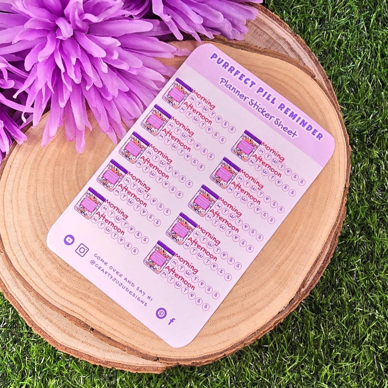 Purple planner stickers sheet on a wooden coaster with purple flowers on grass