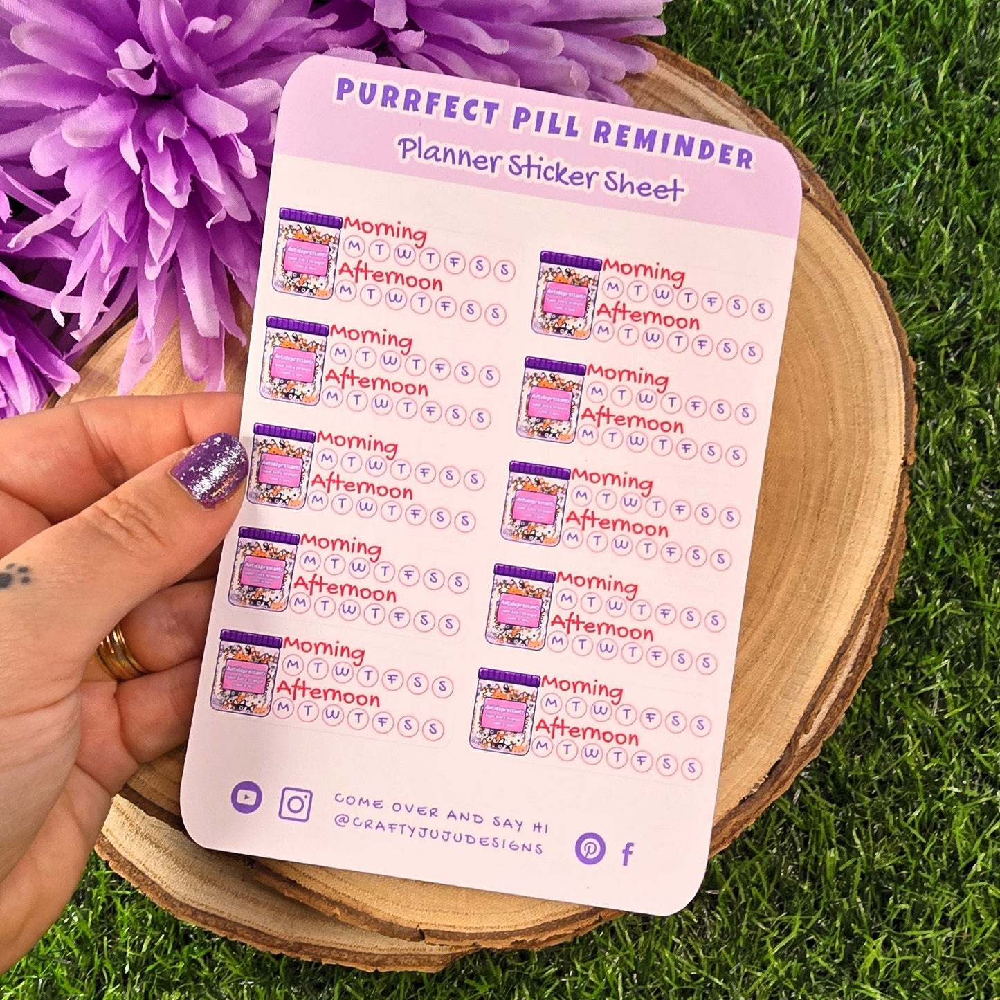 Purfect Pill Reminder planner sticker sheet held over a purple flower on grass