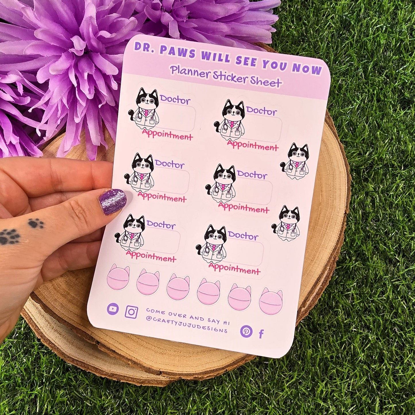 Sheet of planner stickers with dog illustrations held over a purple flower on grass