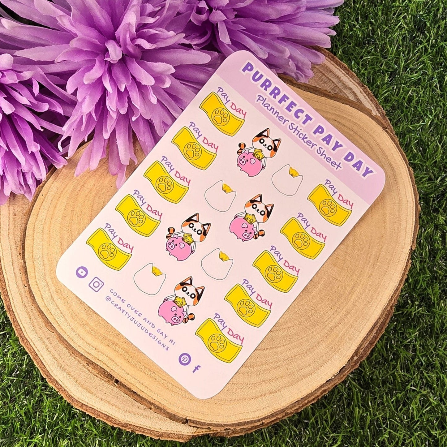 Sheet of planner stickers with 'Purrfect Day' design on a wooden surface with purple flowers in the background.