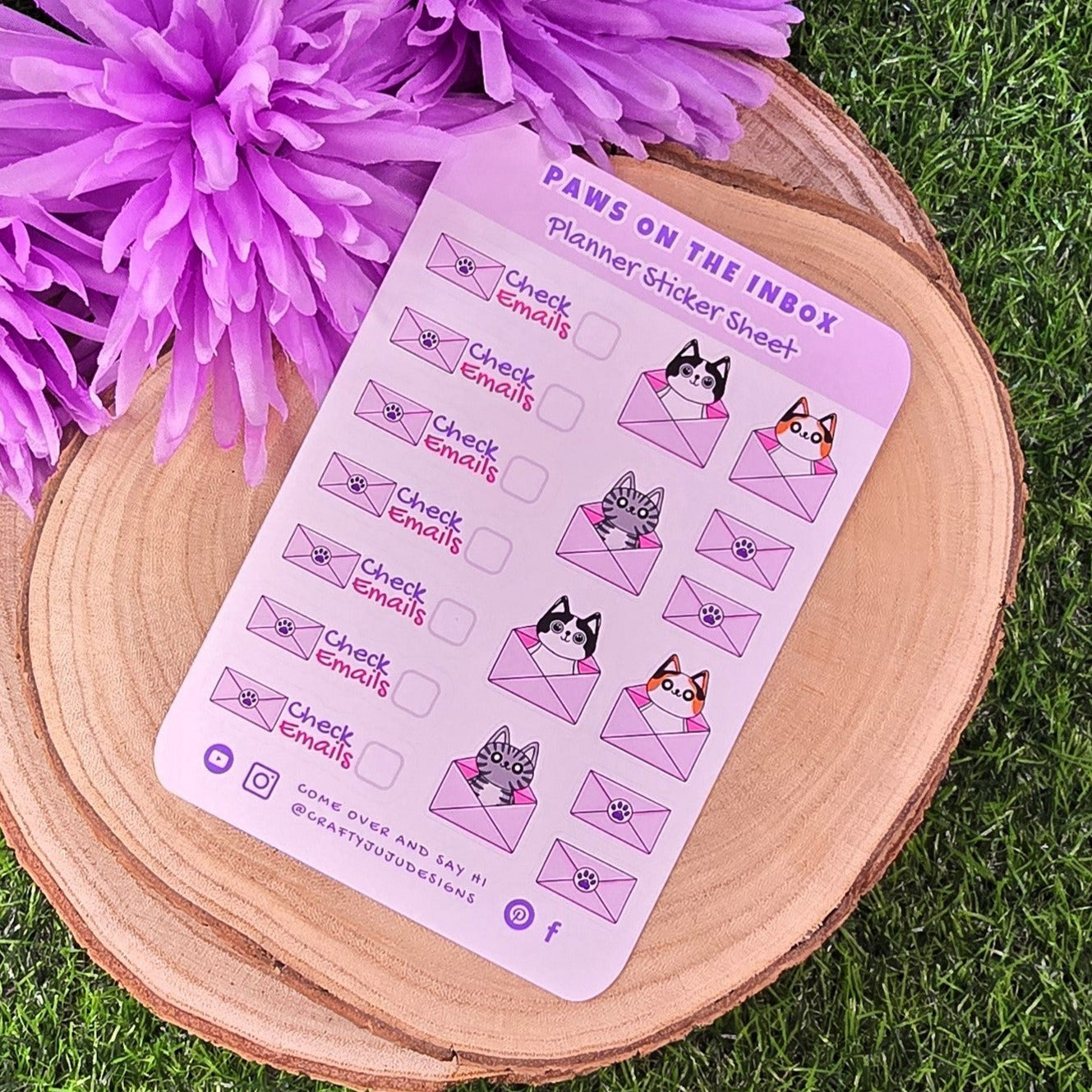 planner sticker sheet paw-themed designs on a wooden stand with purple flowers on grass