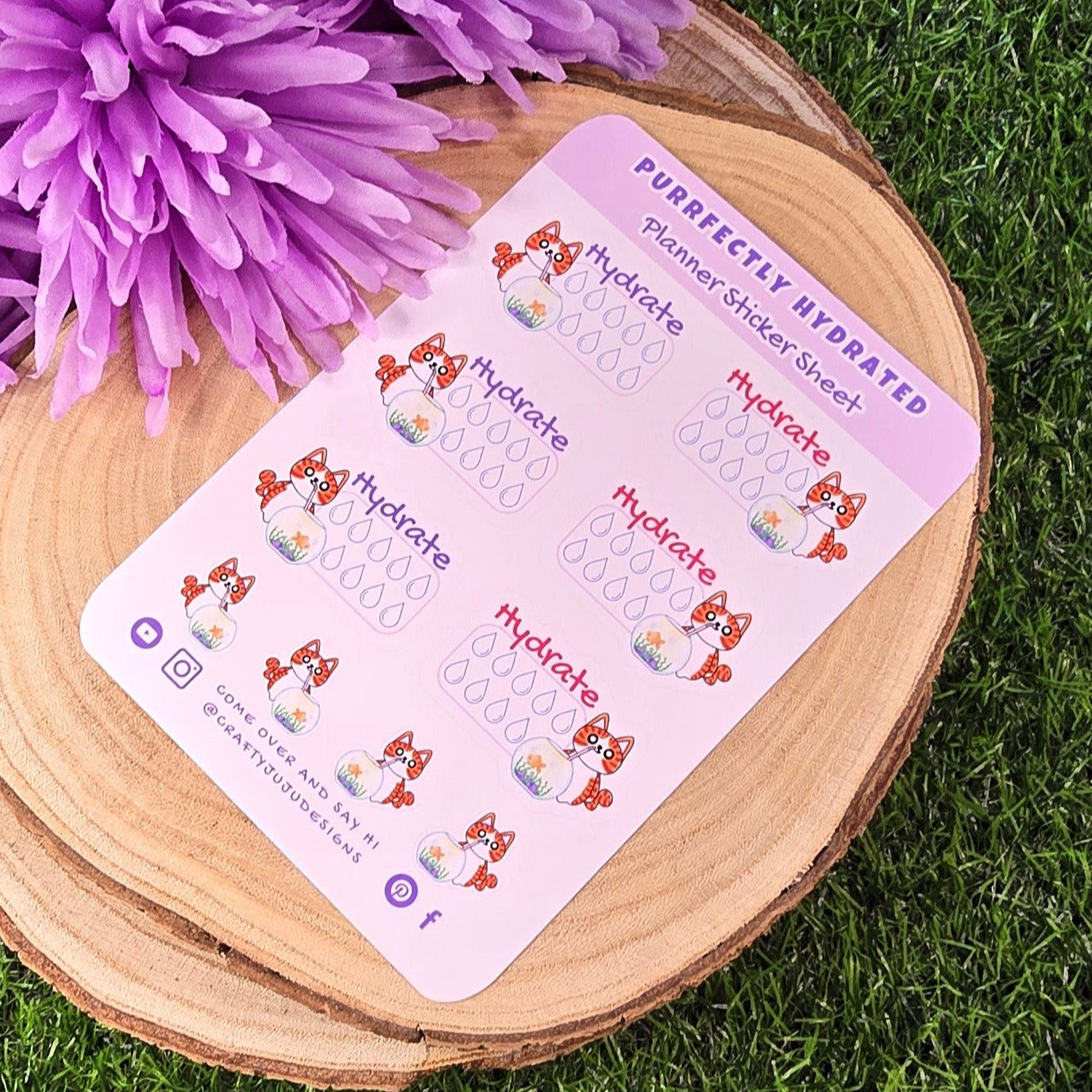 planner sticker sheet on a wooden board with purple flowers on grass.