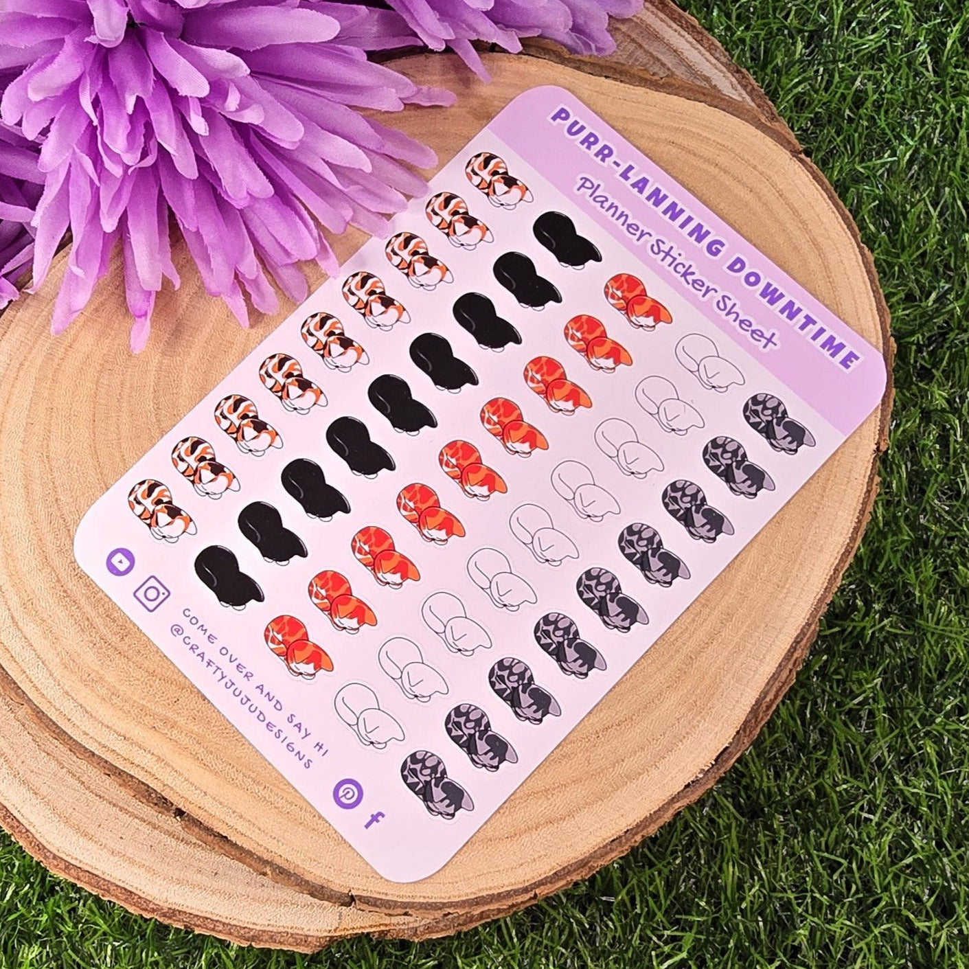 Sticker sheet with various designs on a wooden board with purple flowers on grass