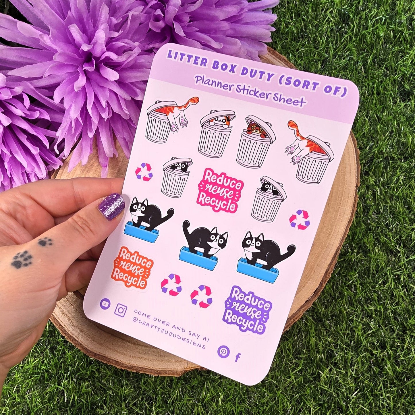 Sheet of stickers with cat-themed designs held over a purple flower and green grass background