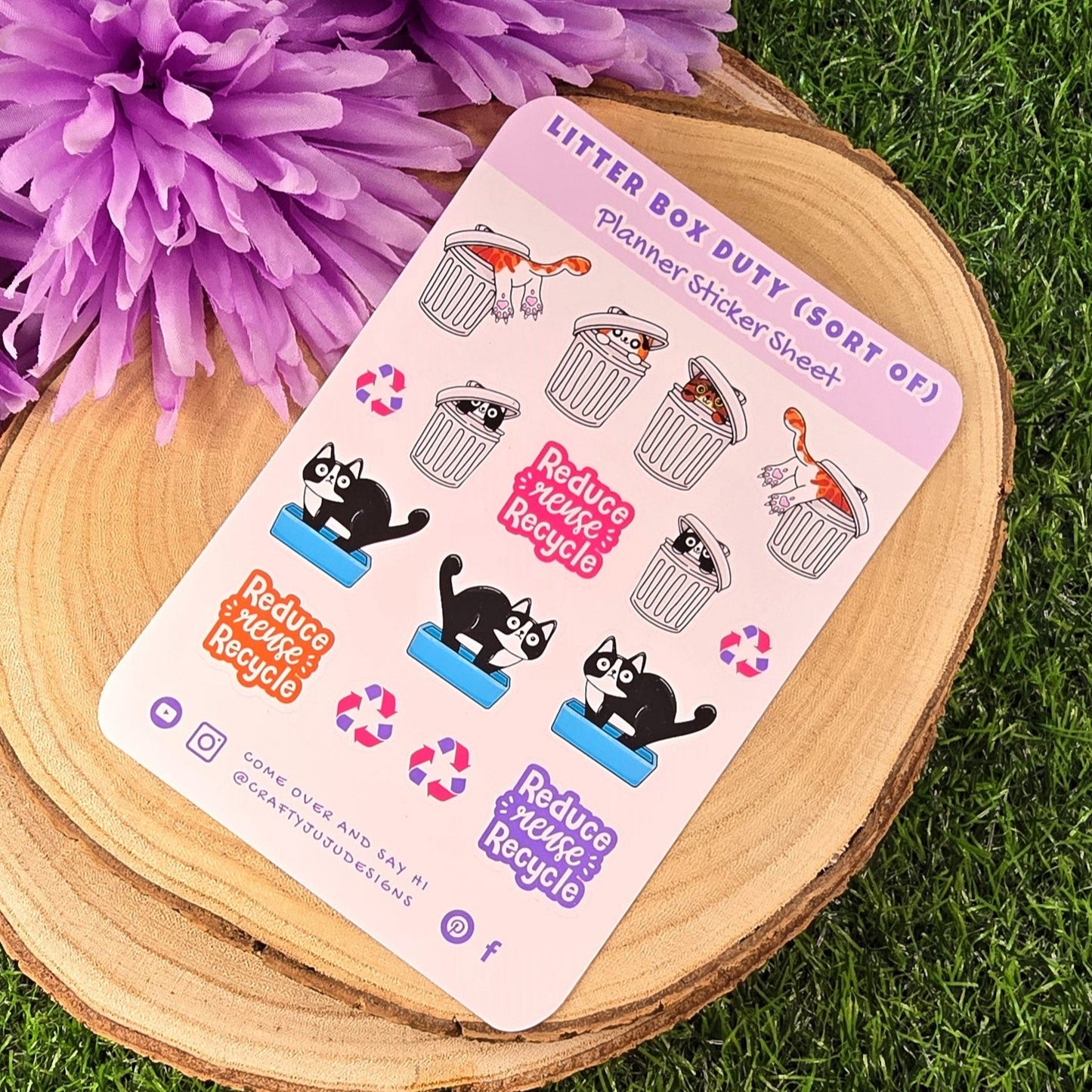 Sticker sheet with cat-themed designs on a wooden stand with purple flowers in the background