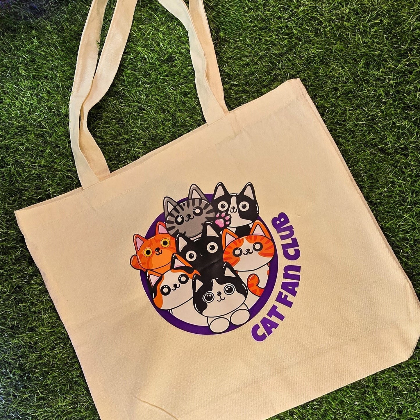 tote bag with cat-themed design and 'Cat Fan Club' text on grass