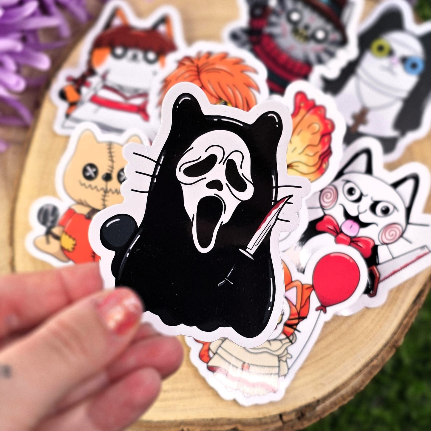 Collection of Halloween-themed stickers on a wooden surface with purple flowers in the background.
