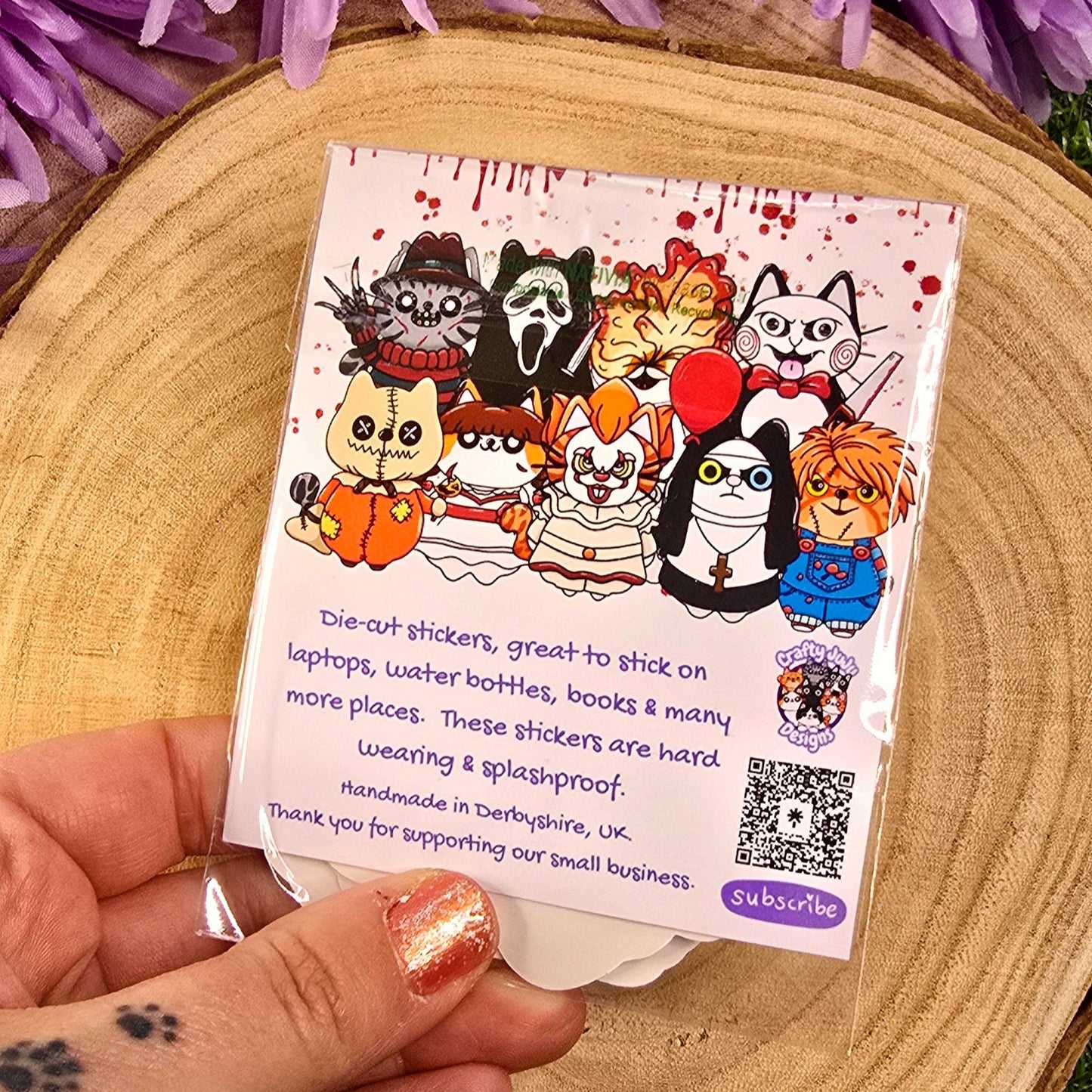 Card with cartoon characters held by a hand against a purple flower background
