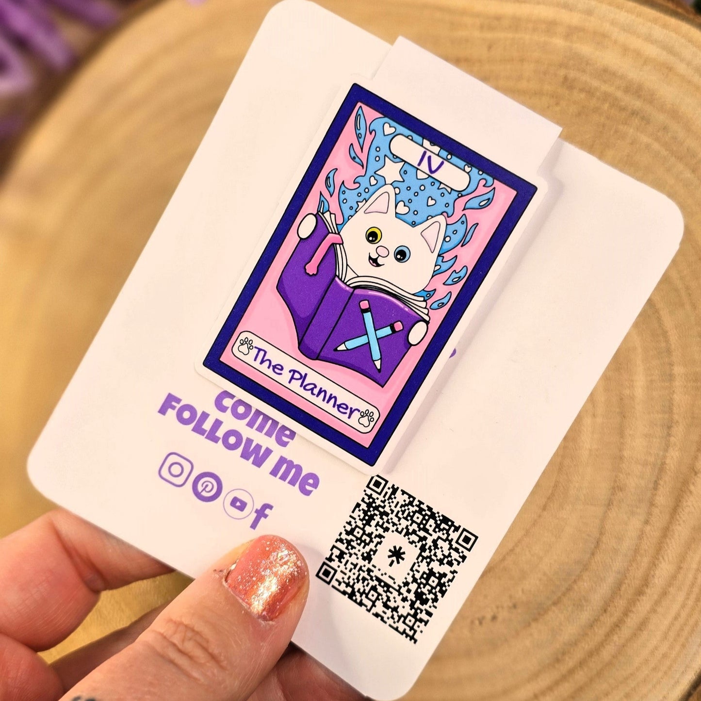 Card with a cartoon cat design and QR code held by a hand, with purple flowers in the background.