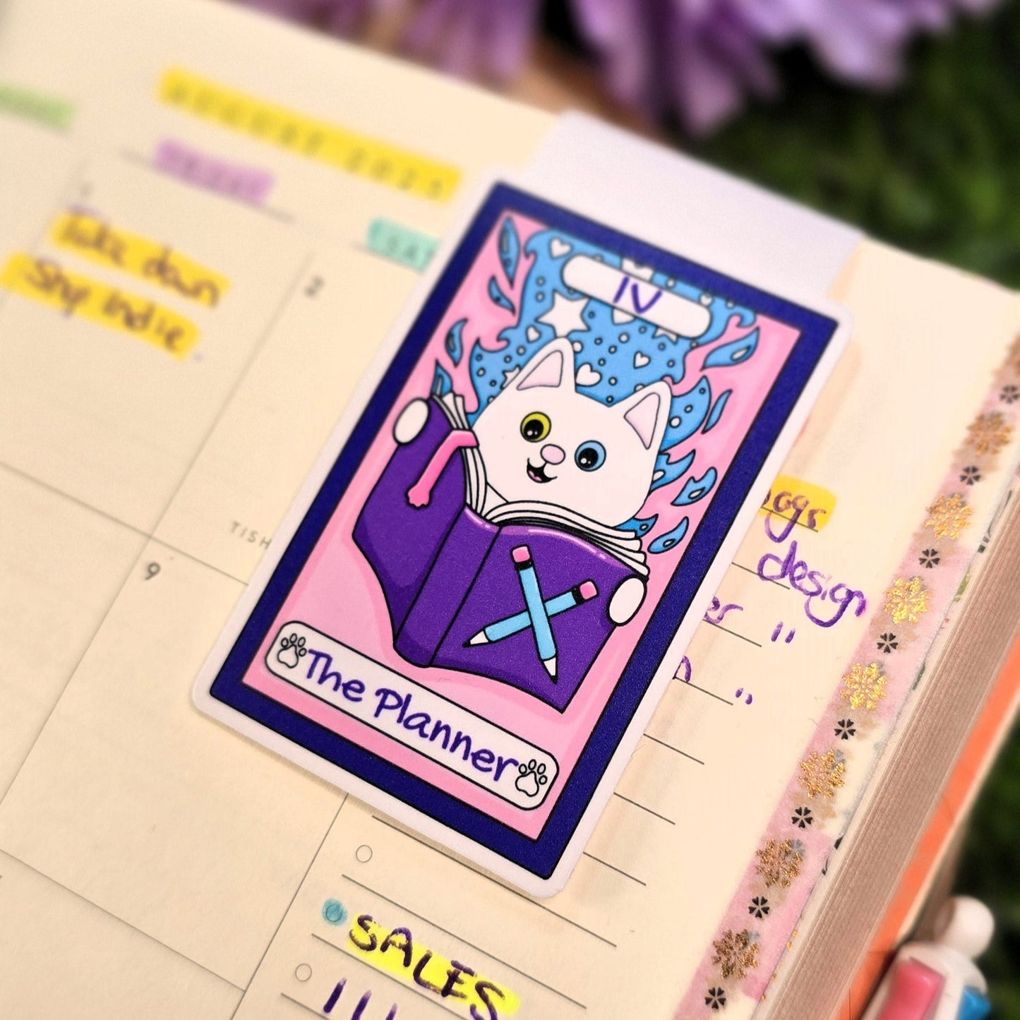 Notebook with a planner sticker featuring a cat character on a grassy background