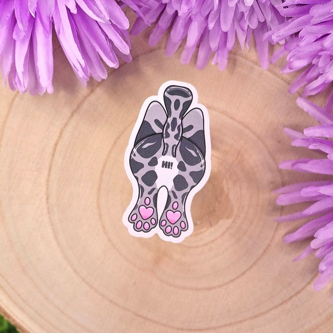 cat-shaped stickers on a wooden surface with purple flowers in the background.