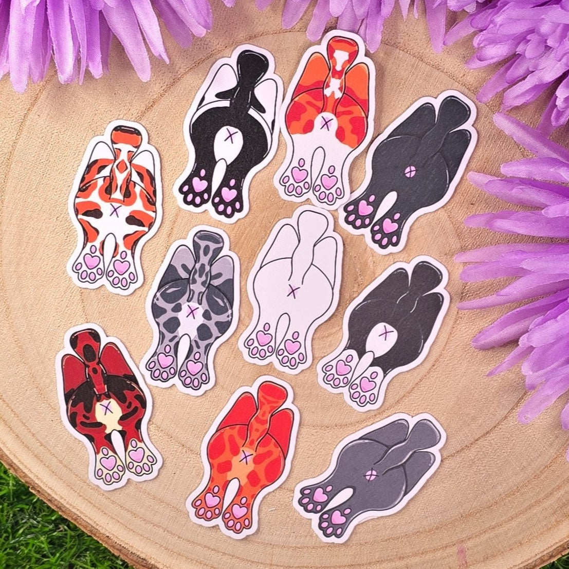 Sticker pack with cats showing off their butts illustrations on a wooden log with purple flowers in the background