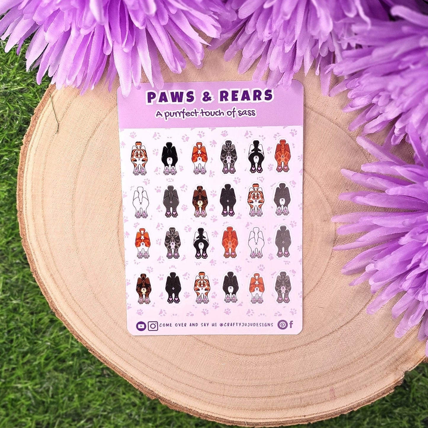 heet of 'Paws & Rears' stickers on a wooden surface with purple flowers.