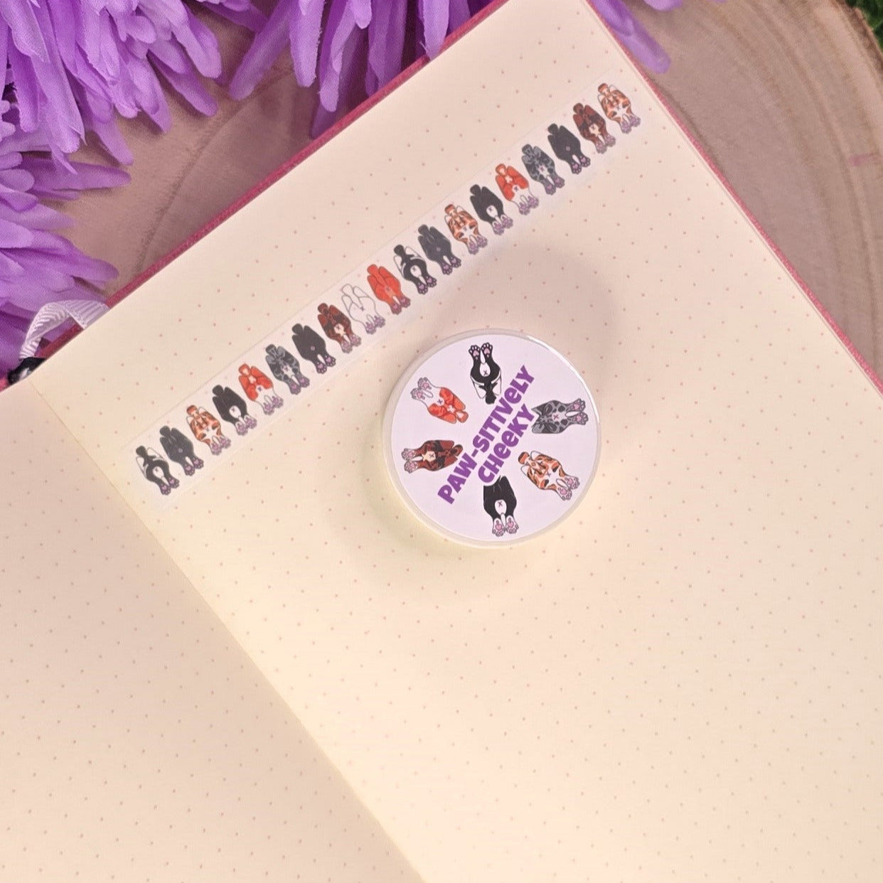 washi tape with cat buts on, resting on a book with purple flower in the background.