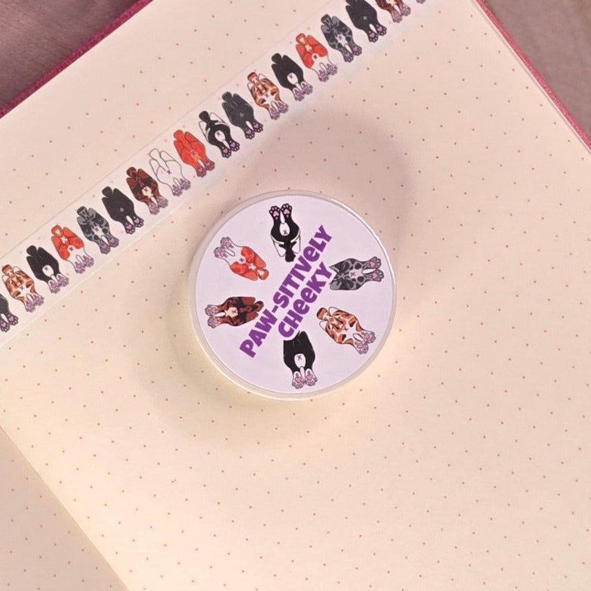 washi tape with cat buts on, resting on a book with purple flower in the background.