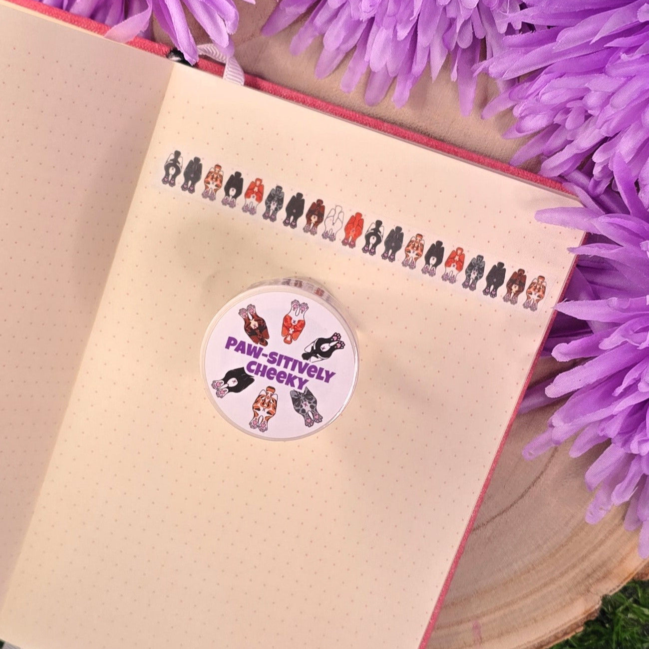 washi tape with cat buts on, resting on a book with purple flower in the background.