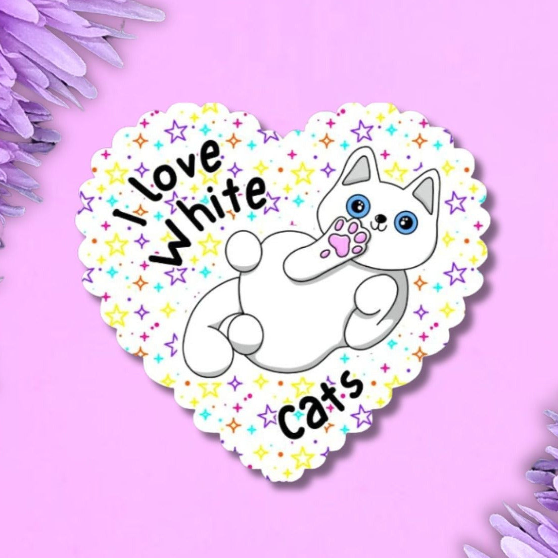 I love white cats heart shaped sticker with a scalloped edge. The background is white with multi coloured stars. The white cat is showing off their belly