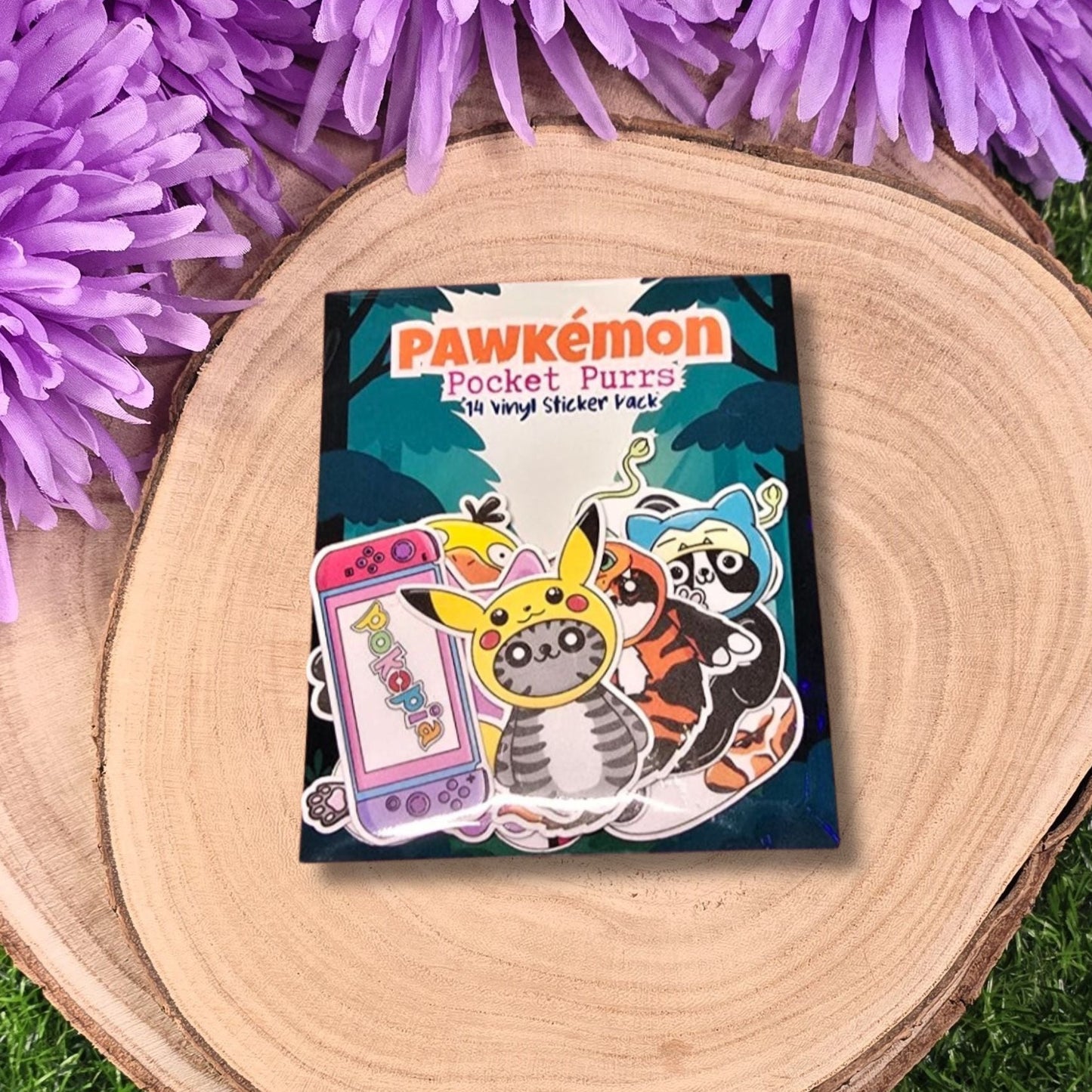 Pawkémon Pocket Puzzles sticker pack on a wooden surface with purple flowers
