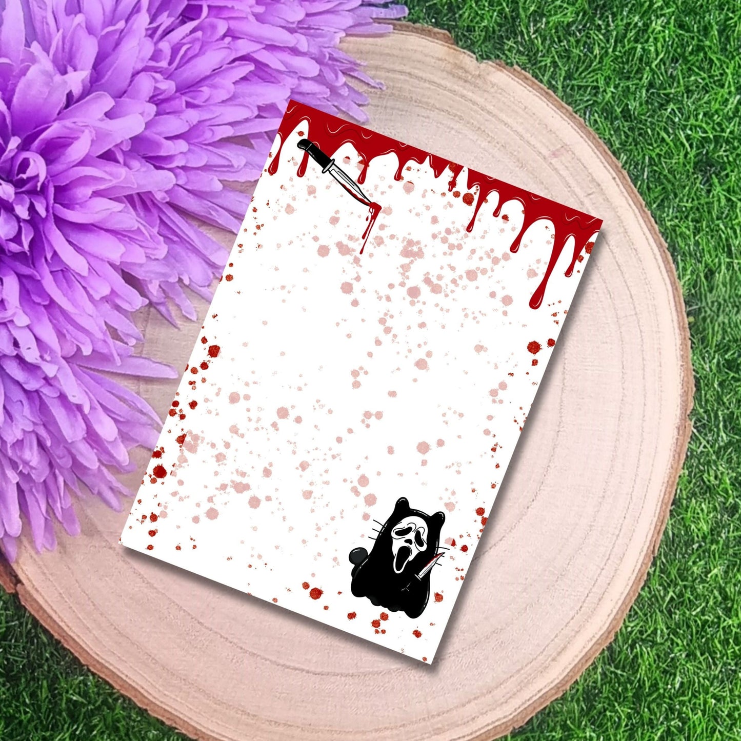 Notebook with a Bloody Handprint design on a wooden surface with a purple flower.