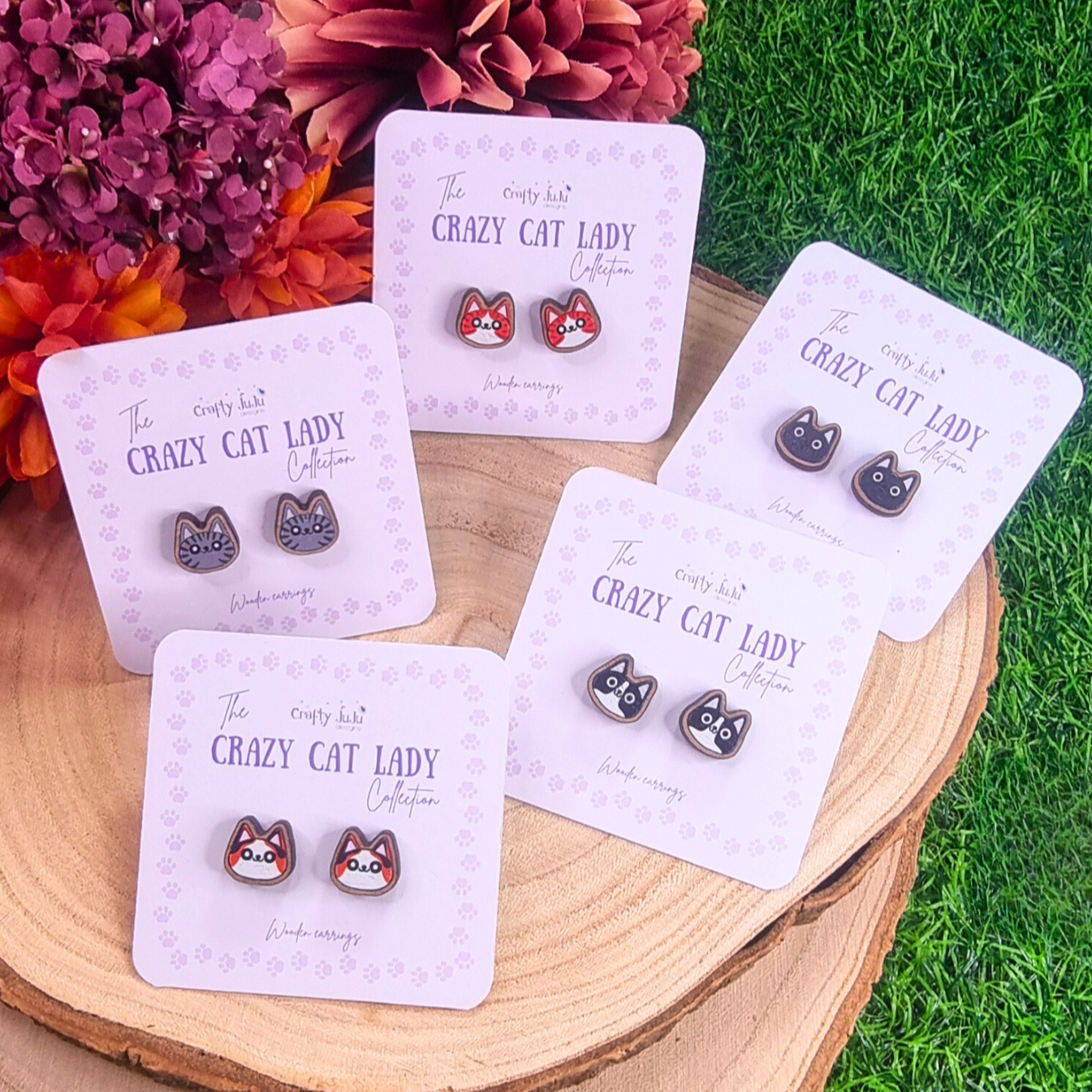 6 pairs of wooden cat earrings, grey cat, black and white cat, tortoiseshell cat, black cat and ginger and white cat. Each pair is on a light purple backing card with The Crazy Cat Lady Collection labelled