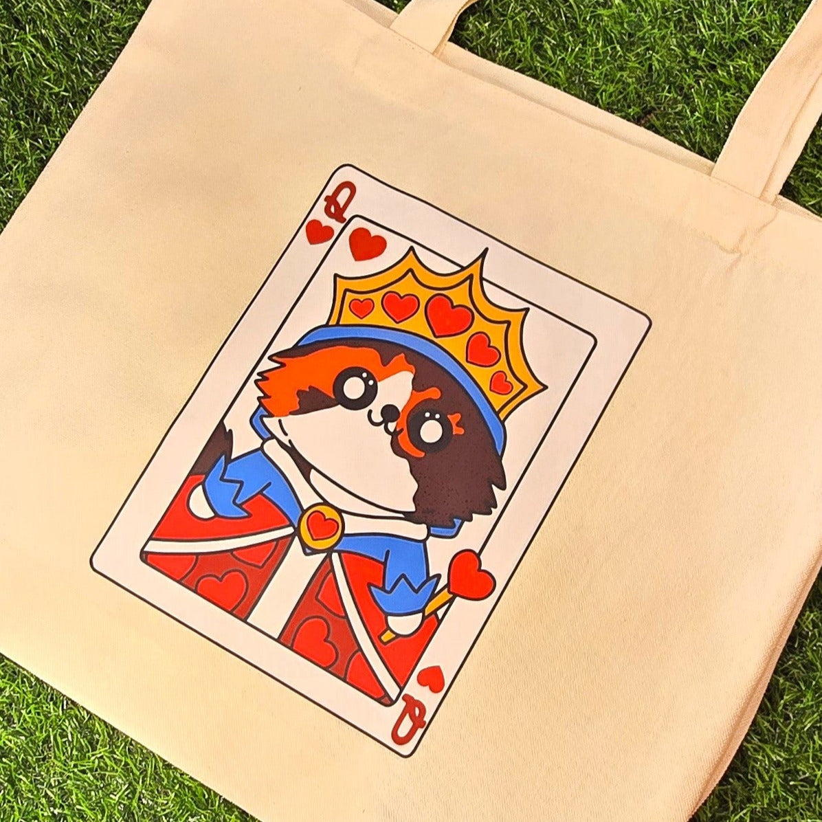 Beige tote bag with a card-themed design of a dog on a grassy surface.