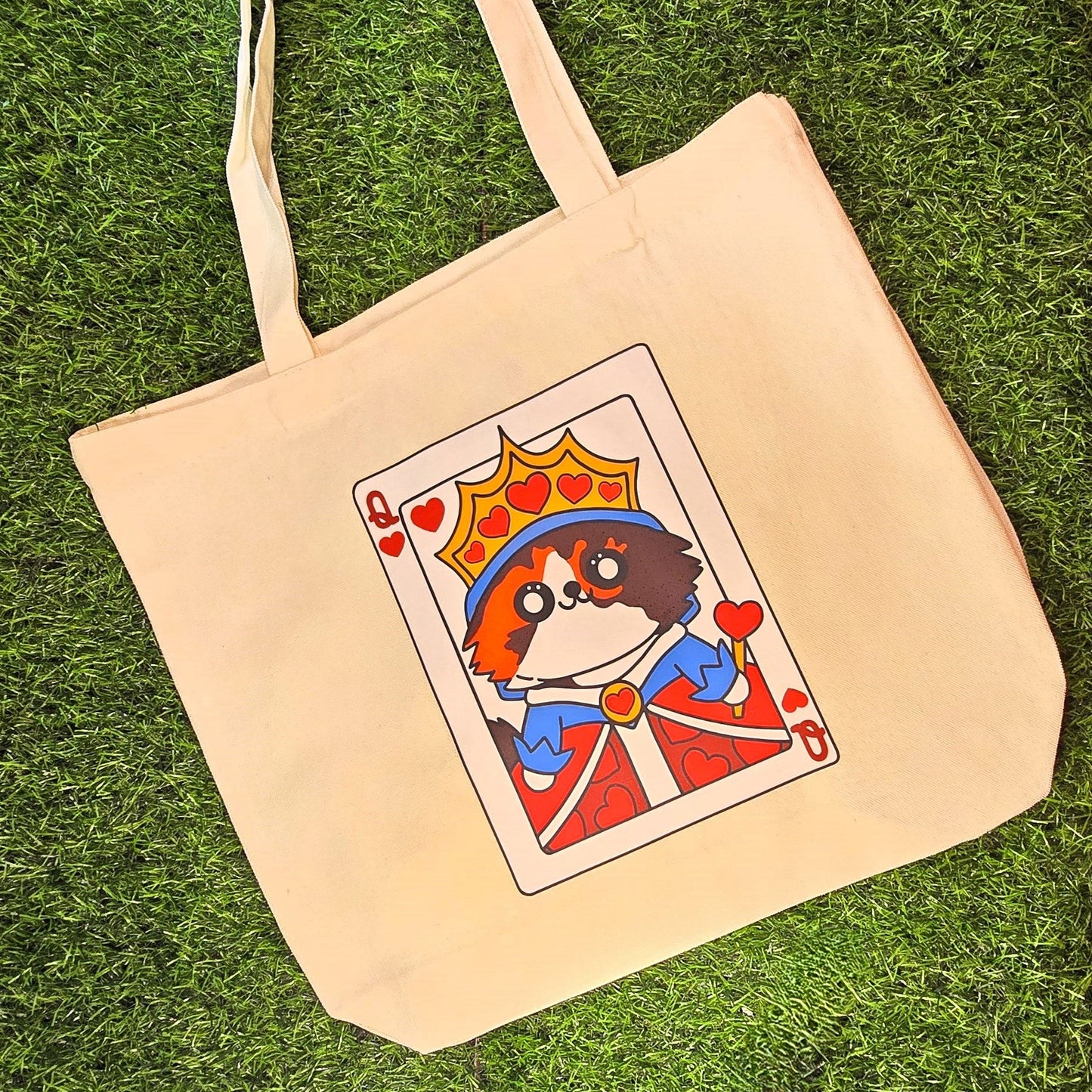 Beige tote bag with a card design featuring a cat on a grass background
