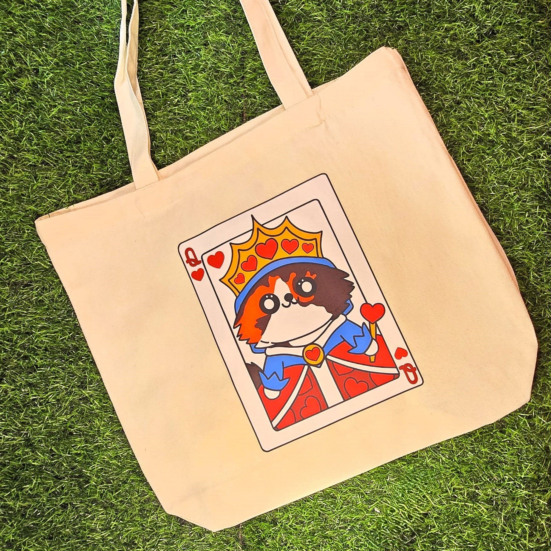 Beige tote bag with a card design featuring a cat on a grass background