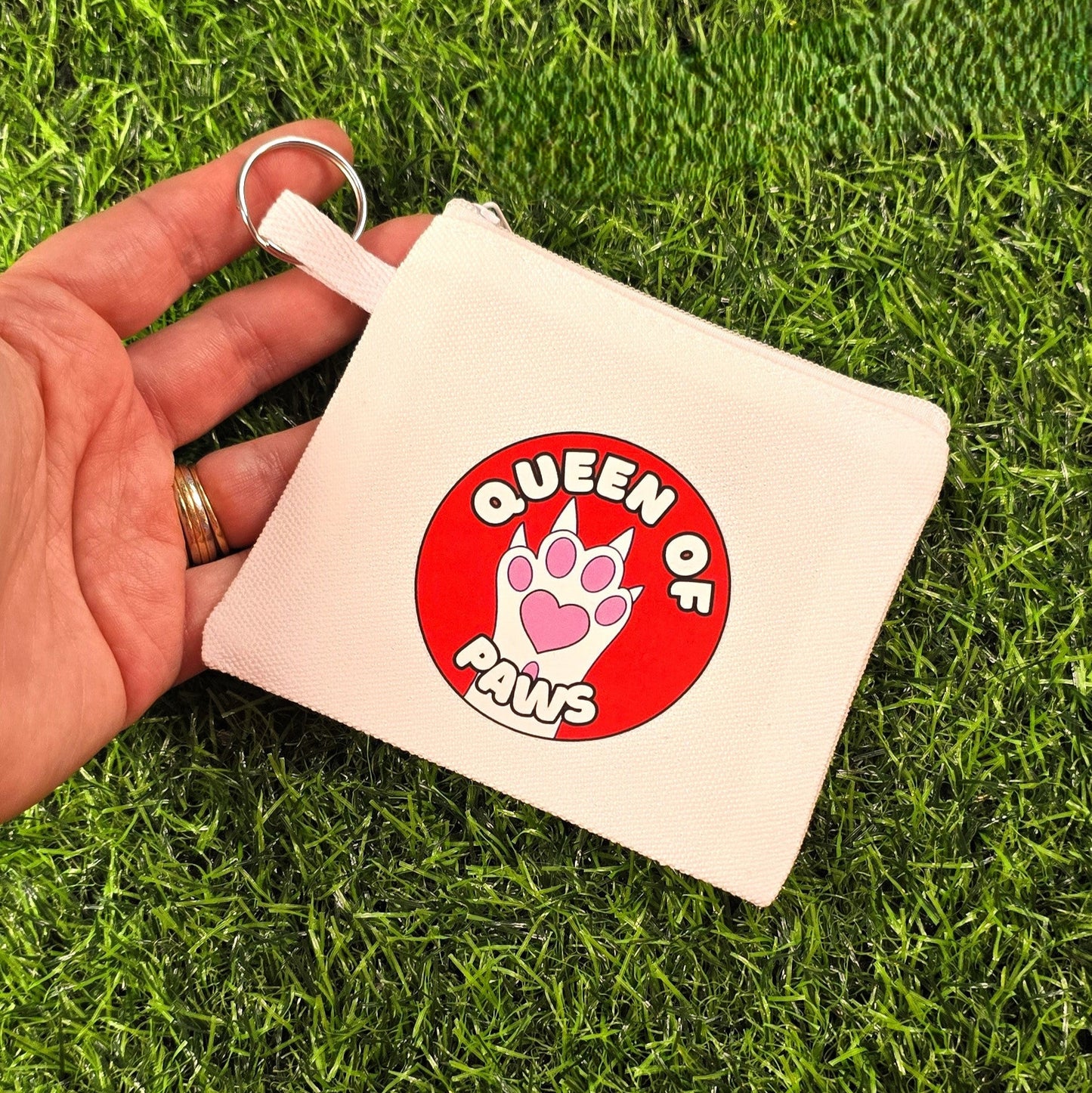Keychain with 'Queen of Paws' design on a grass background