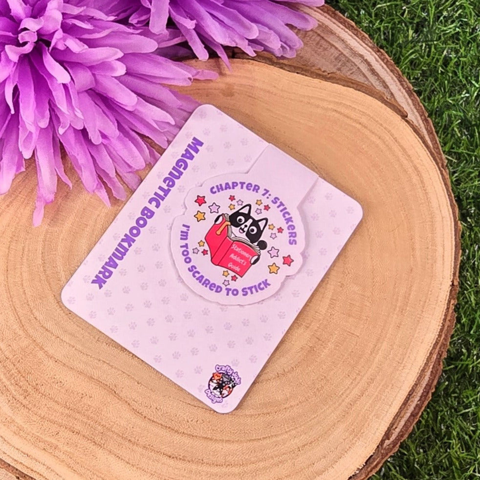 cat bookmark on a wooden disc with purple flowers in the background
