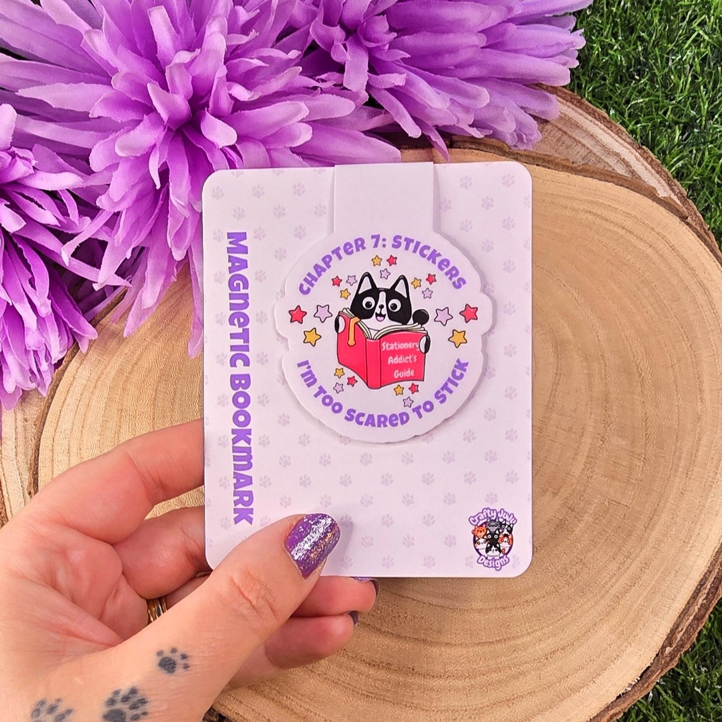 Magnetic bookmark with a cartoon character on a wooden surface with purple flowers