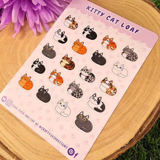 Sticker sheet with cat illustrations on a wooden surface with purple flowers