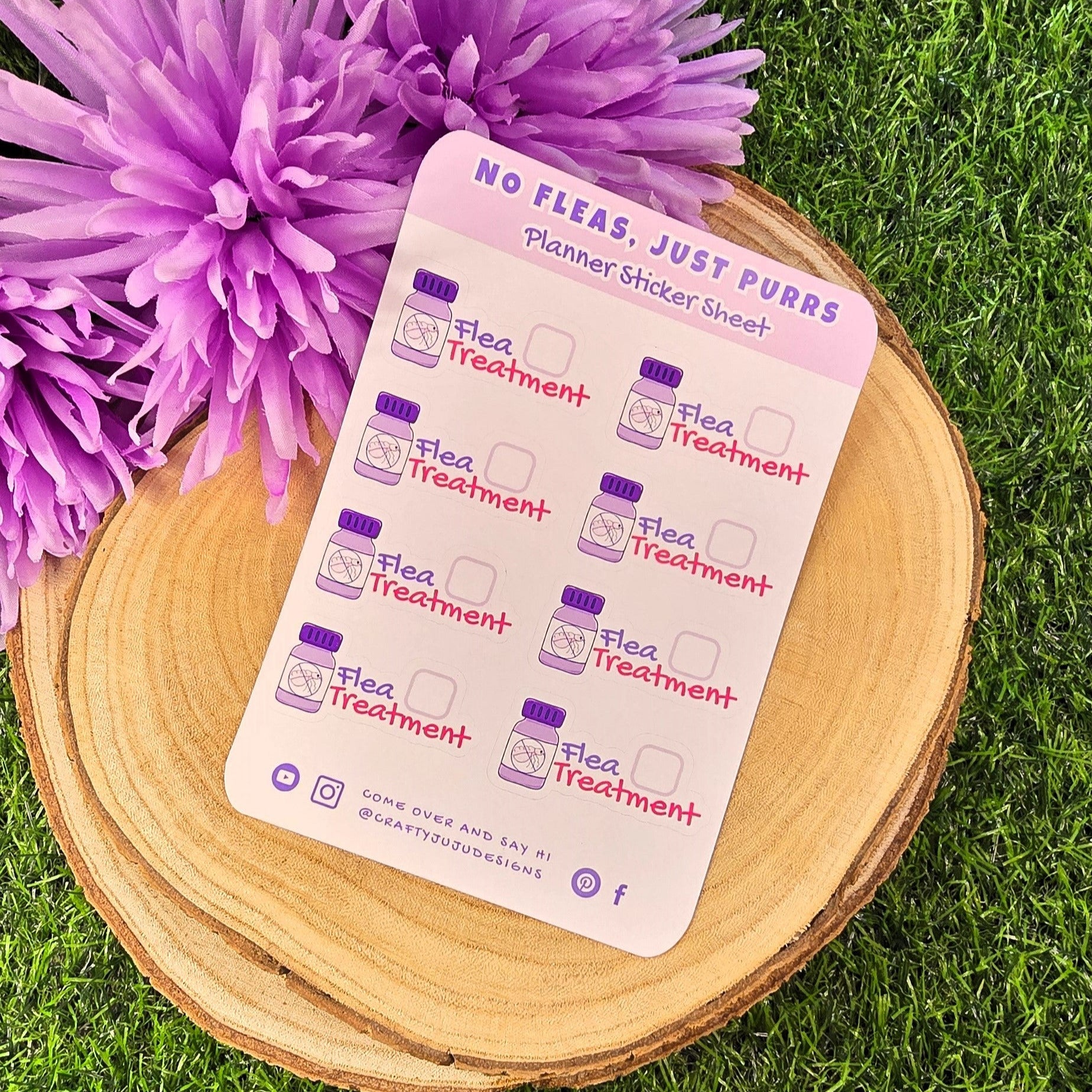 planner sticker sheet with flea treatment illustrations on a wooden surface with purple flowers