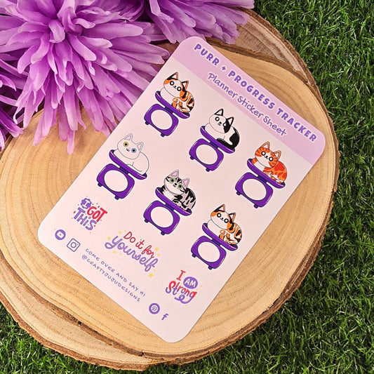 planner stickers on a wooden coaster with purple flowers on grass