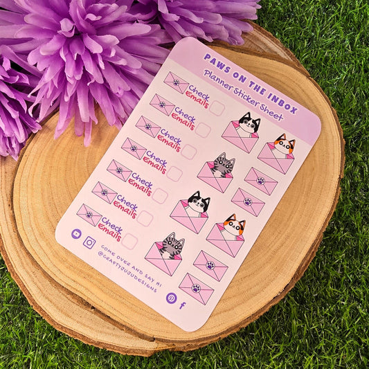 Sheet of planner stickers with cat-themed design on a wooden surface with purple flowers.