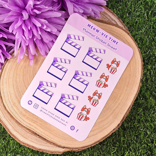 Sticker sheet with planner stickers on a wooden surface with purple flowers