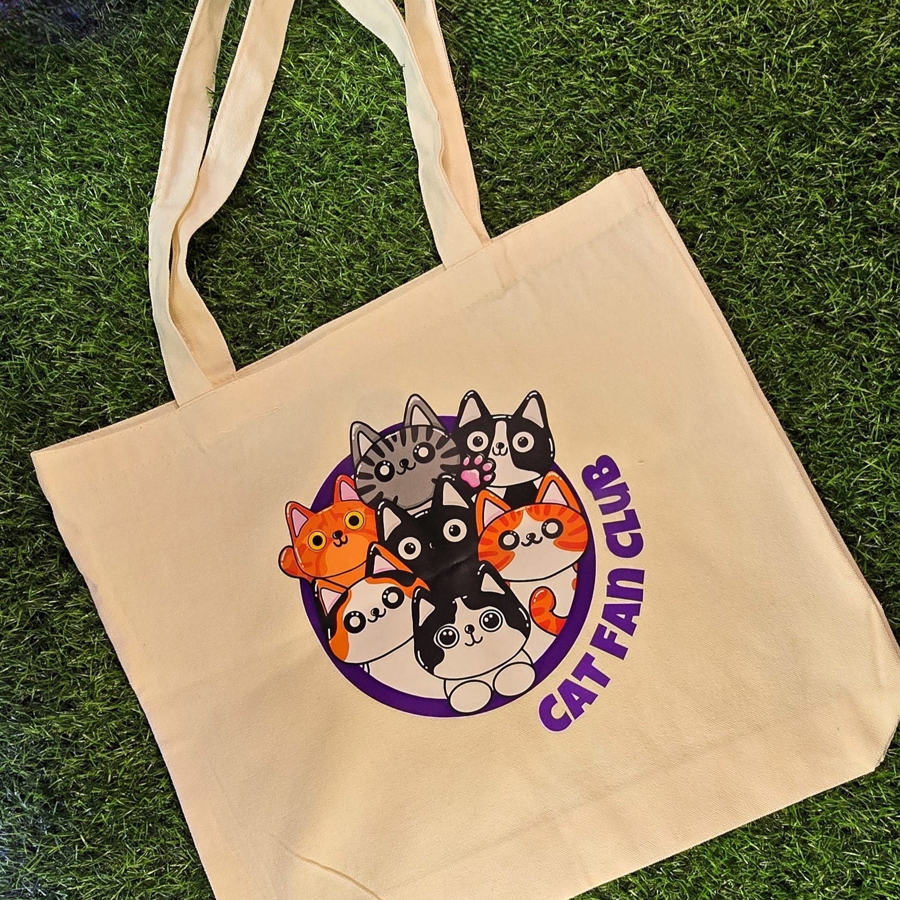  tote bag with cat-themed design and 'Cat Fan Club' text on grass
