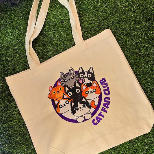  tote bag with cat-themed design and 'Cat Fan Club' text on grass