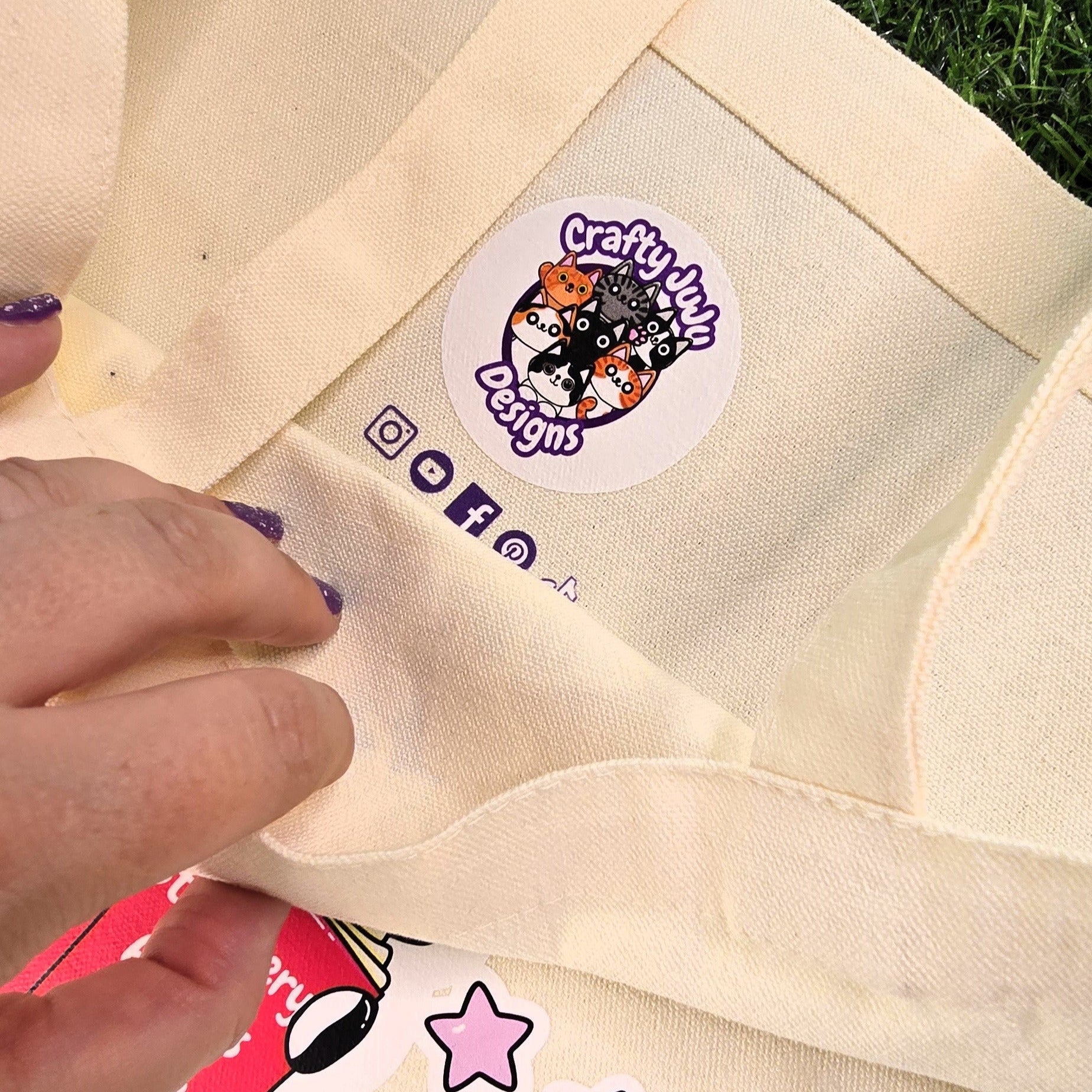 Beige tote bag with a brand label on grass