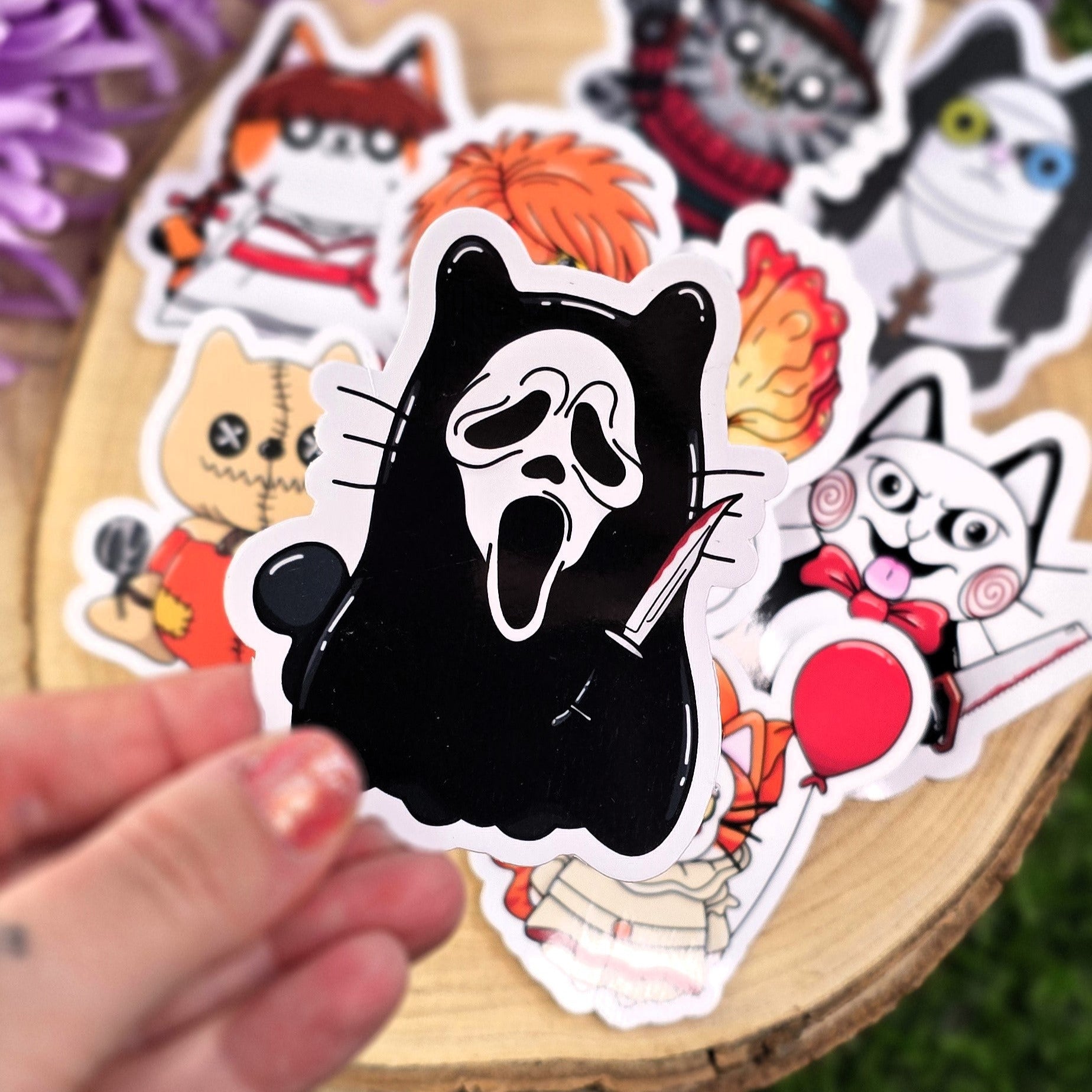 Collection of Halloween-themed stickers on a wooden surface with purple flowers in the background.