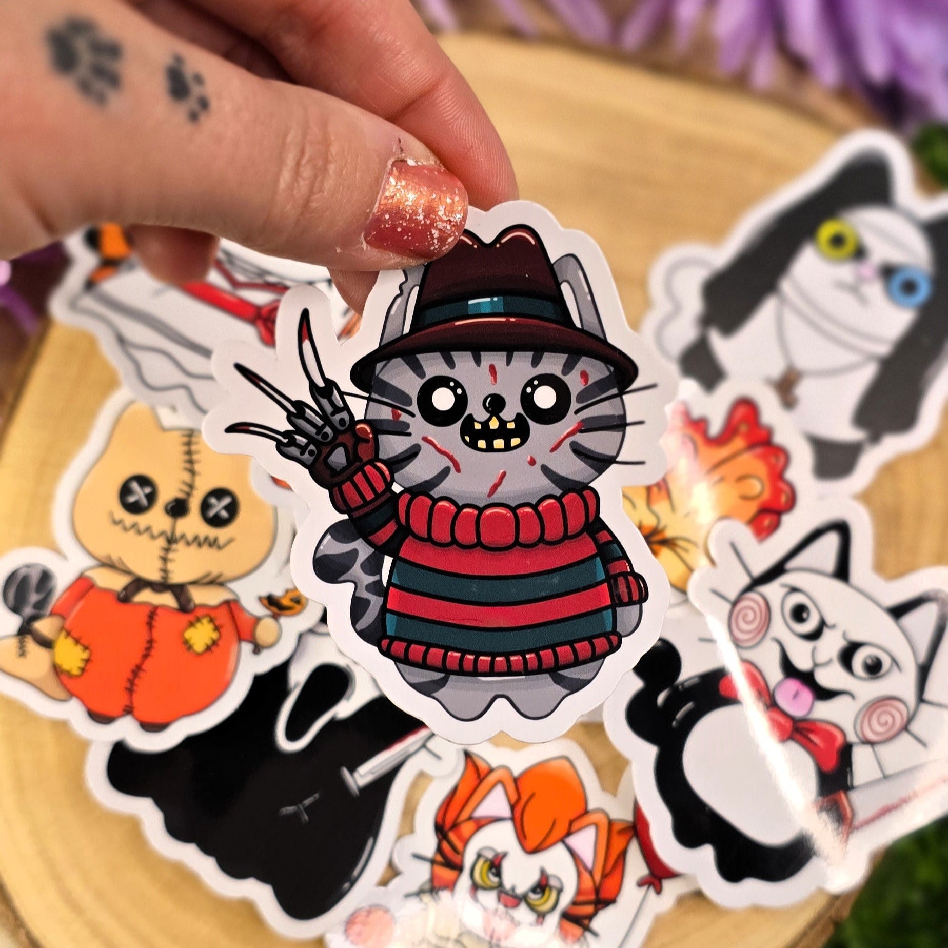 Collection of Halloween-themed stickers on a wooden surface with purple flowers in the background.
