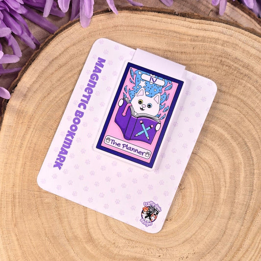 Magnetic bookmark with cartoon cat design on a wooden surface with purple flowers