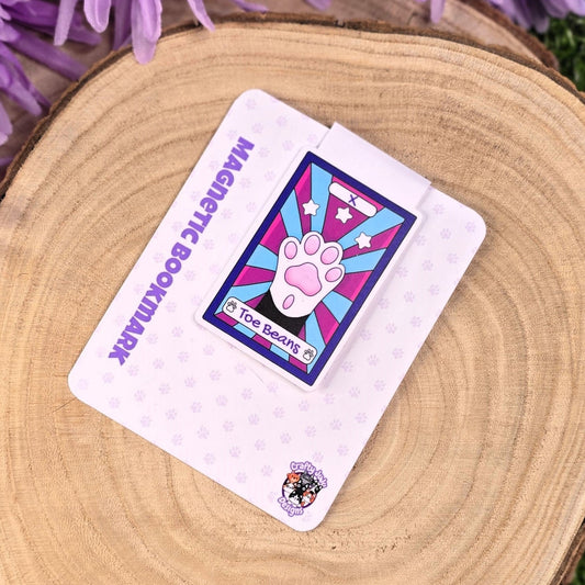 magnetic bookmark with a colorful design on a wooden surface with purple flowers in the background