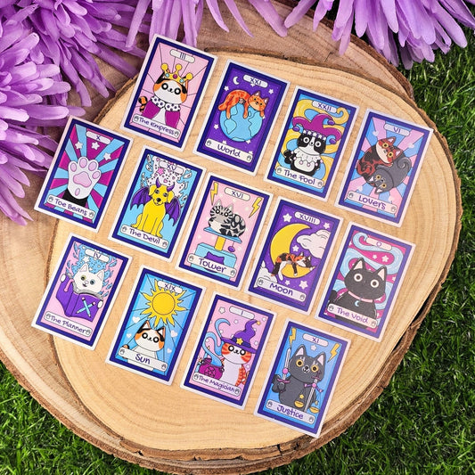Set of colorful tarot card stickers with cartoon characters on a wooden board surrounded by purple flowers.