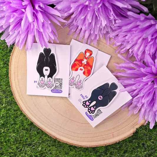 cat butt magnetic bookmarks on a wooden board with purple flowers in the background