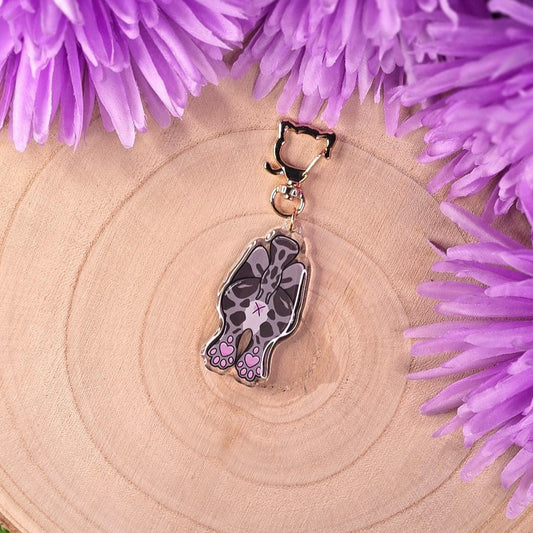cat butt keyring on a wooden surface surrounded by purple flowers