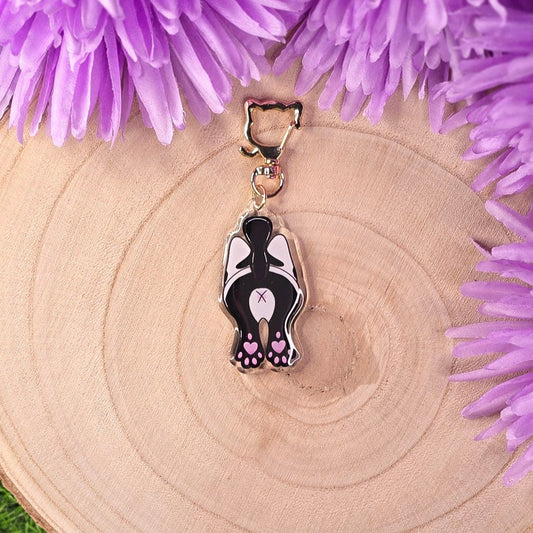Cat-shaped keychain on a wooden surface with purple flowers