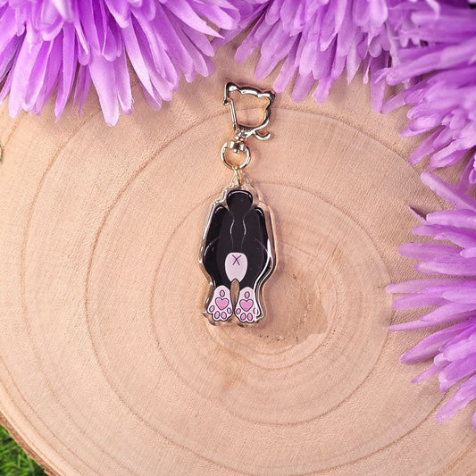 cat butt keyring on a wooden surface surrounded by purple flowers